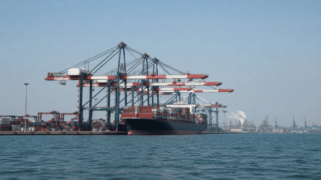 Kinesisk containerhamn med lastfartyg och hamnkranar, sedd från vattnet.