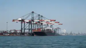 Kinesisk containerhamn med lastfartyg och hamnkranar, sedd från vattnet.